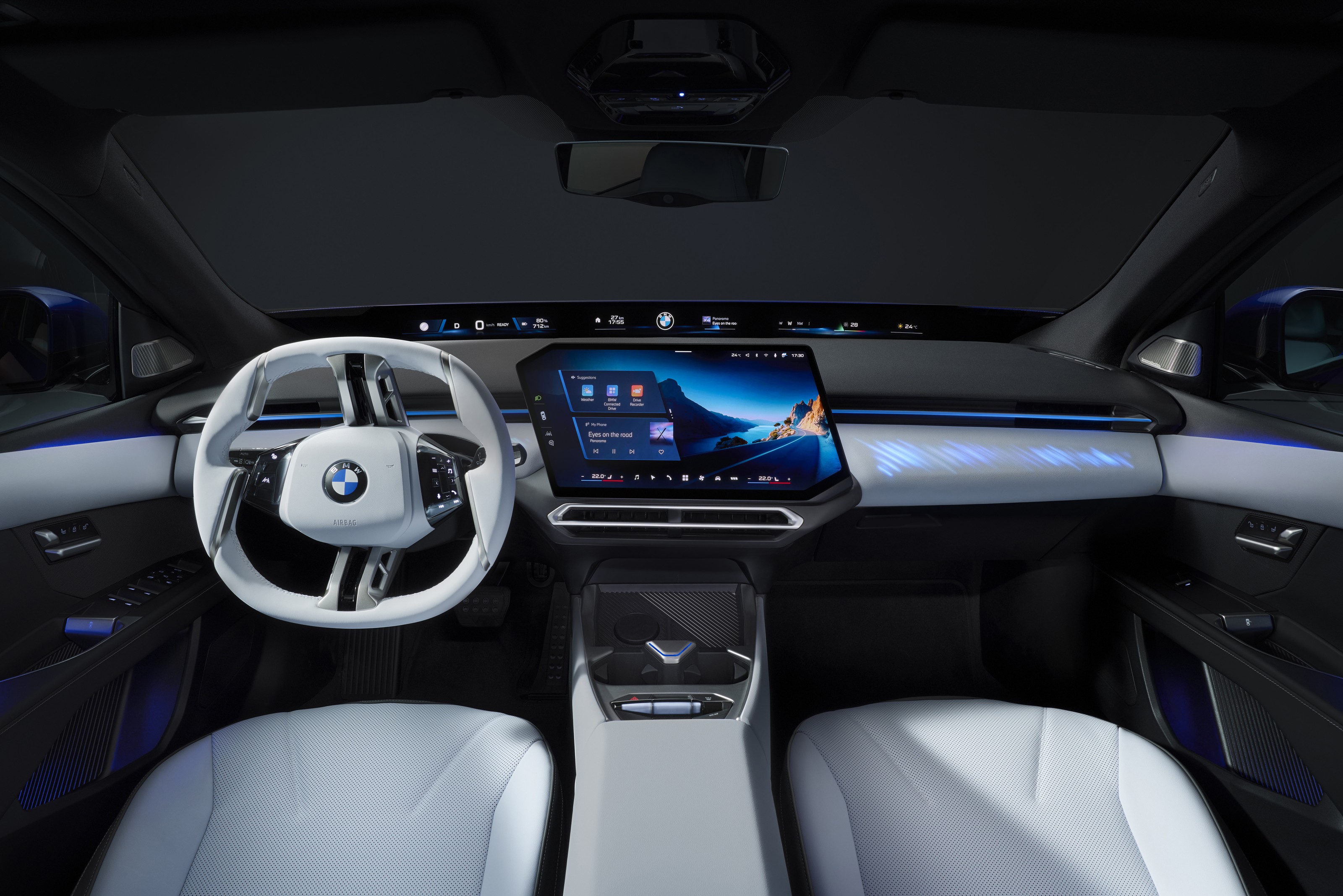 Cabin of the BMW i3 from the rear seat: light-gray steering wheel, a freestanding center touchscreen and a lit display band along the base of the windshield