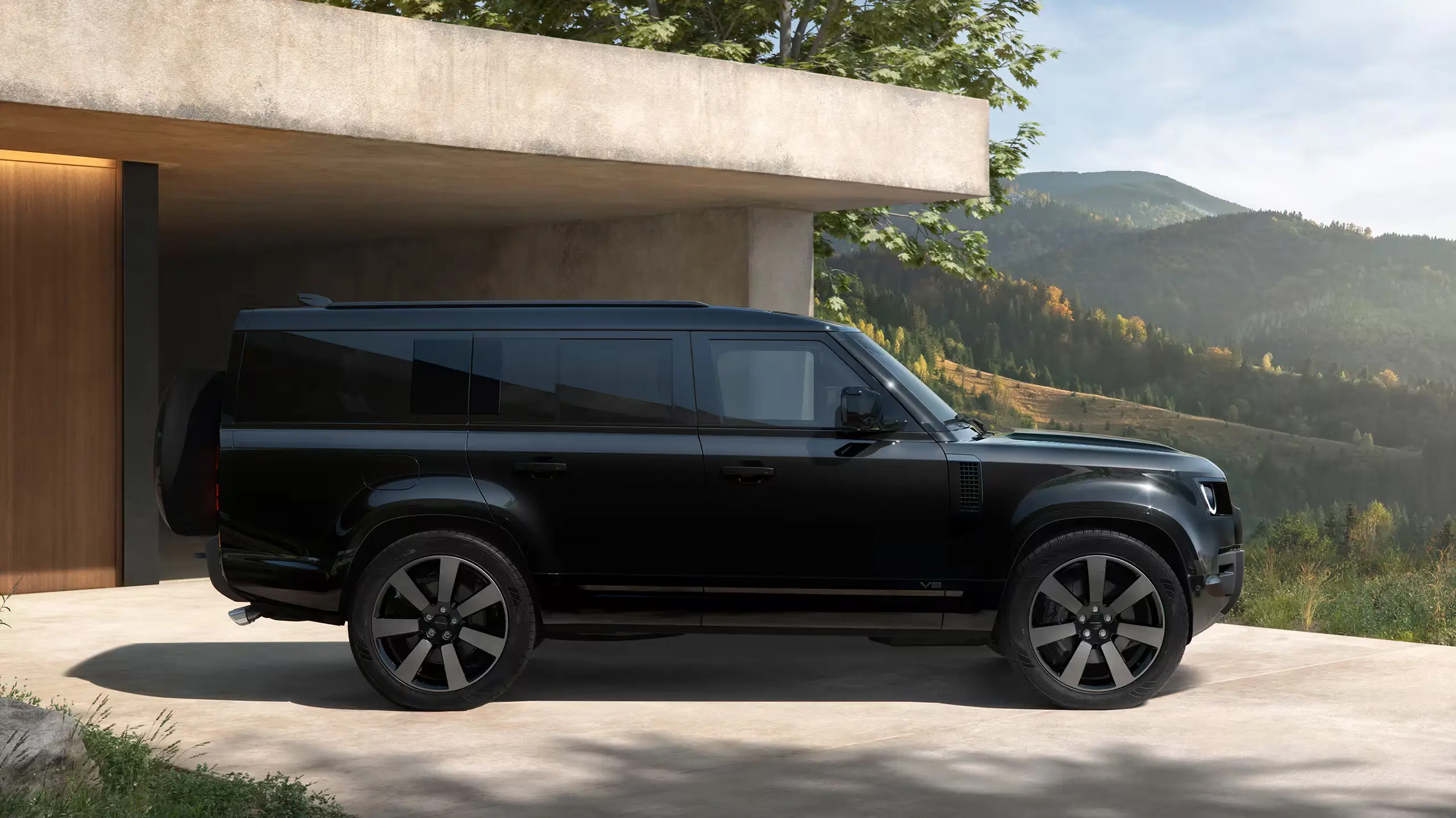 Black Defender 130 beside a modern home overlooking mountains