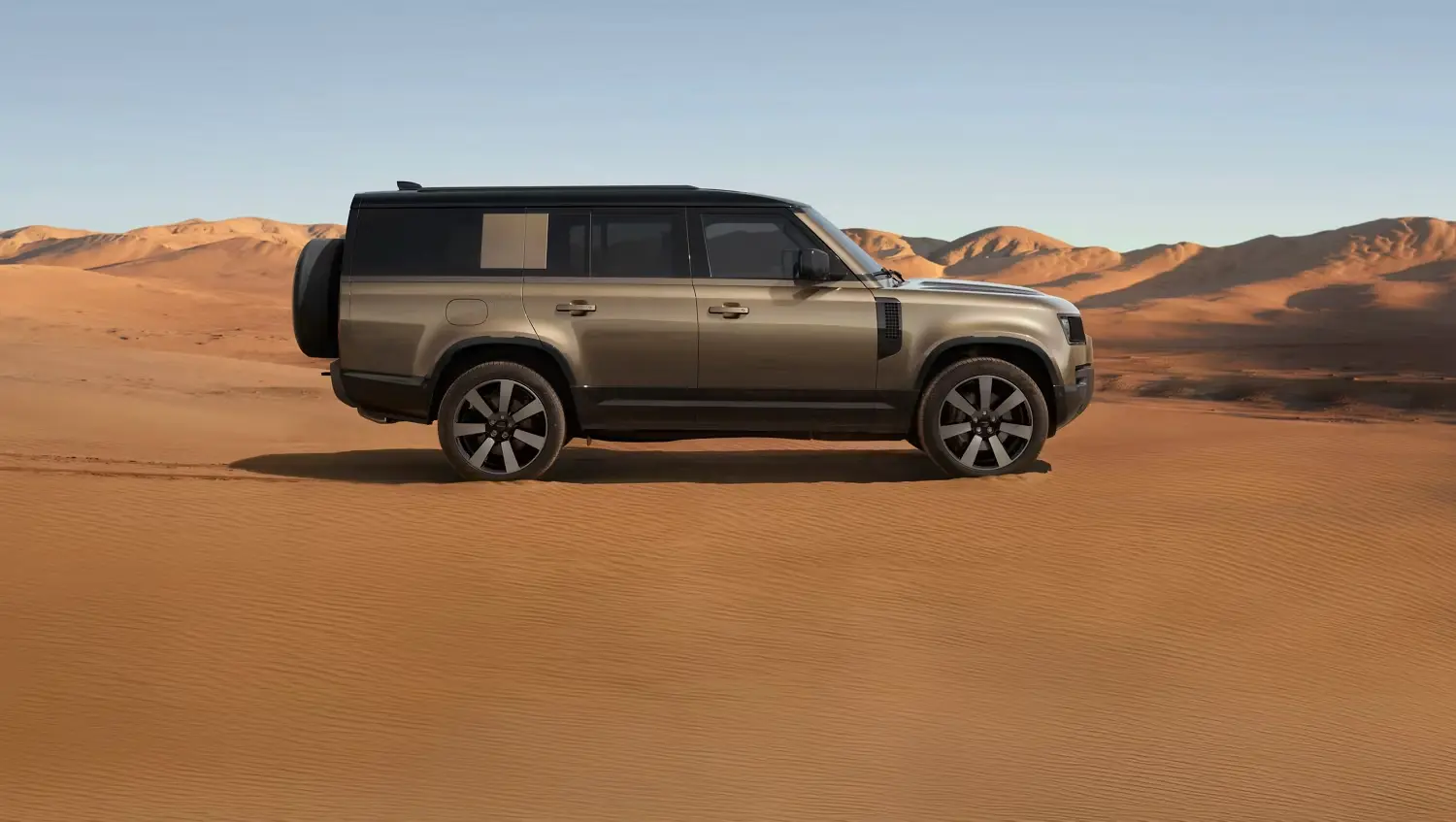 Tan Defender 130 in profile on desert sand