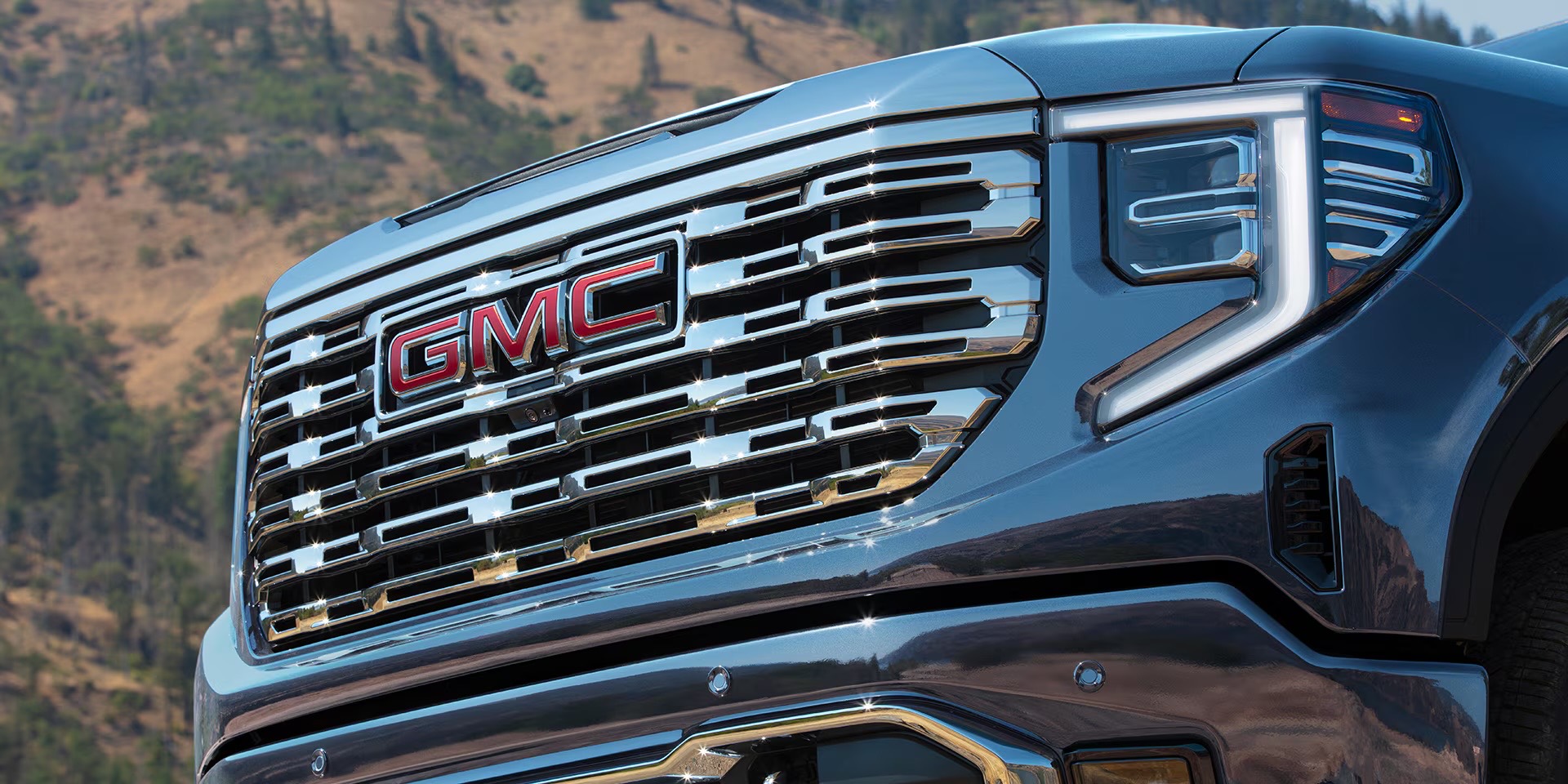 Close-up of the chrome grille and red GMC badge on a 2026 GMC Sierra 1500 Denali